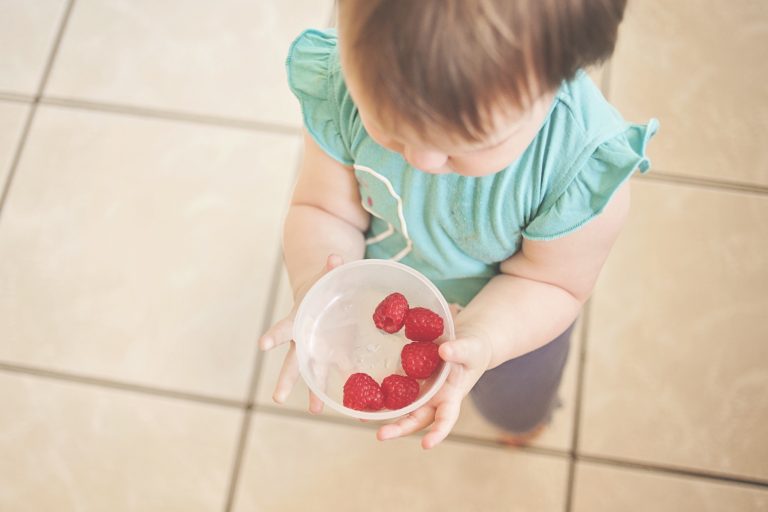 Baby led weaning child holding a bowl of food